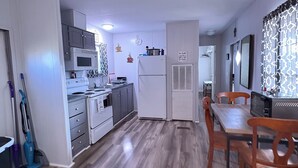 A modern kitchen with a microwave, stove, and refrigerator. There is a dining area with wooden chairs and a table. - Cozy camp on private property minutes from hunting, fishing and restaurants. (Buras)