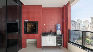 A modern kitchen with red tiles, a water dispenser, and a view of the city.