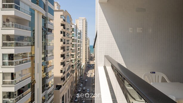 A high-rise building with multiple balconies, a tiled interior, and a view of a street with cars. - Apto 2Q c/ churrasq. 500m da Meia Praia ROT1001 (Itapema)