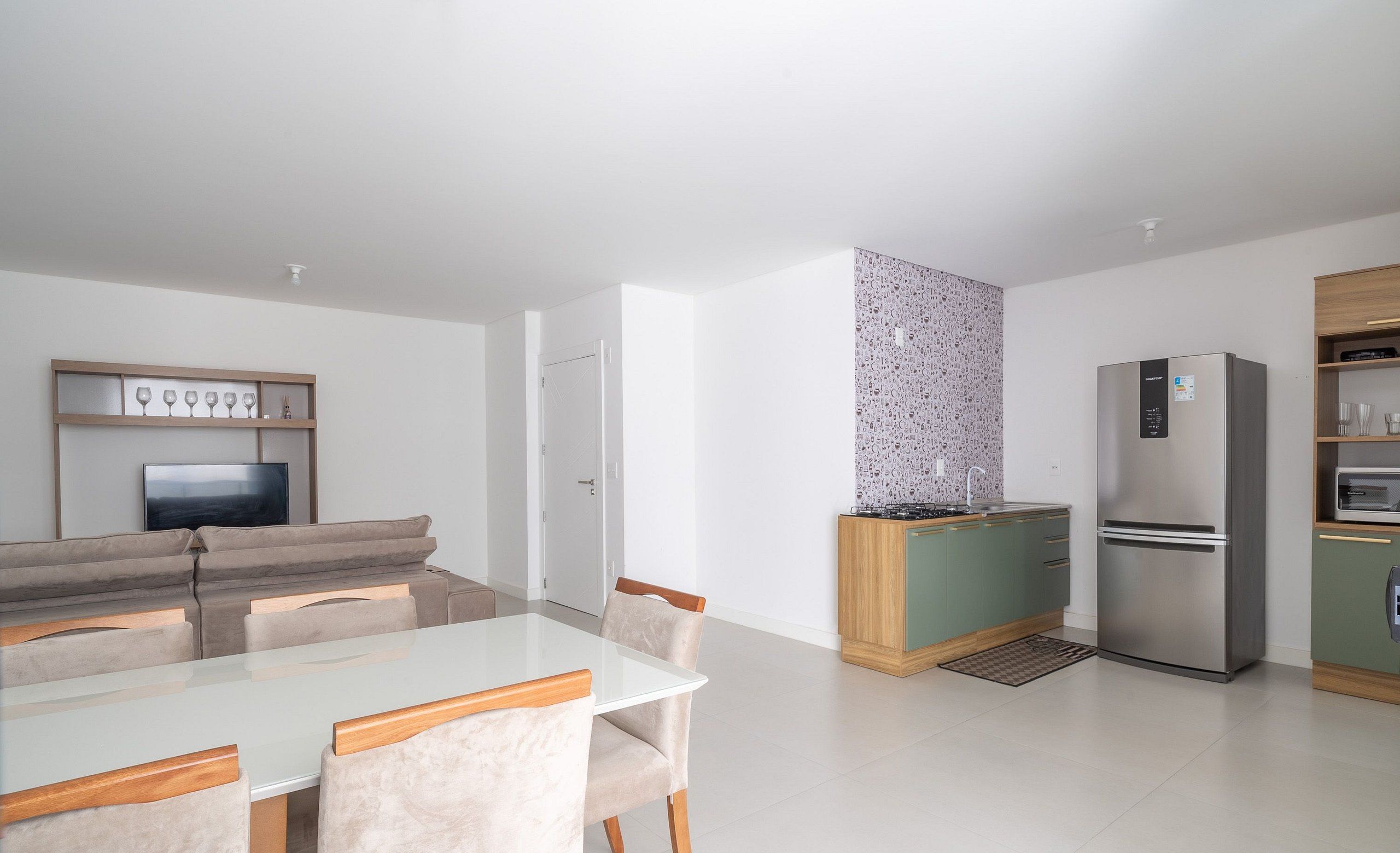 A modern kitchen with a dining area, a built-in TV, and a refrigerator.
