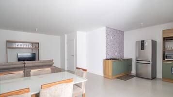 A modern kitchen with a dining area, a built-in TV, and a refrigerator.