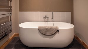 A modern bathroom with a freestanding bathtub, a towel rack, and a tiled shower area.