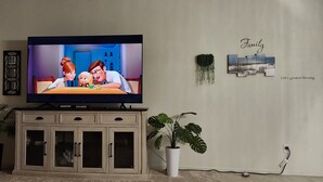 A television on a cabinet, a potted plant, and a wall with a 'Family' sign. - Beautiful and Comfy 4-bedroom house with AC in Maricopa (Maricopa)
