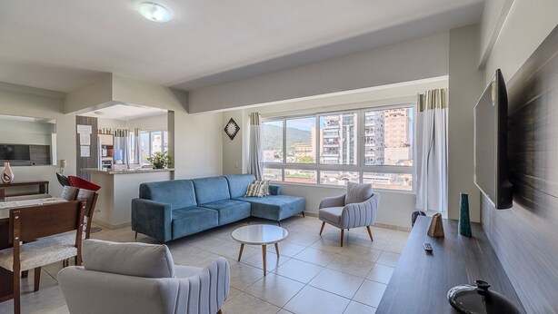Un salon moderne avec un canapé, des fauteuils, une table basse et un téléviseur.