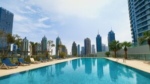 Une piscine avec des chaises longues et, en arrière-plan, la silhouette de la ville.