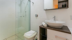 A modern bathroom with a glass shower enclosure, a white sink, and a wooden vanity.