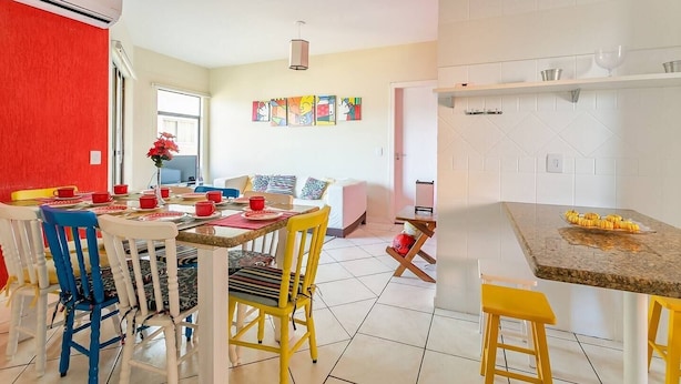 A bright dining area with a table set for four, surrounded by colorful chairs.