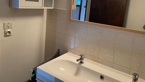 A bathroom with a white sink, a mirror, and a cabinet with lights.