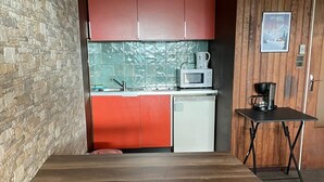 A compact kitchen with a microwave, coffee maker, and a small table.