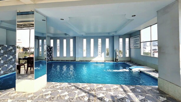 An indoor swimming pool with clear blue water, tiled floor, and large windows allowing natural light. - FOUR SEASONS HOTEL NHA TRANG (Nha Trang)