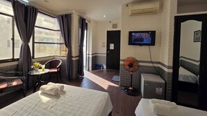 A hotel room with two beds, a desk with a chair, a TV on the wall, and a fan. - FOUR SEASONS HOTEL NHA TRANG (Nha Trang)