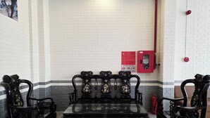 A room with a black sofa set, a small table, and a red fire extinguisher on the wall. - FOUR SEASONS HOTEL NHA TRANG (Nha Trang)