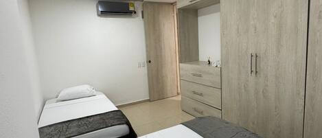 A bedroom with two beds, a wardrobe, and a mirror.