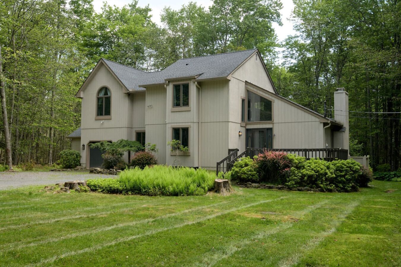 A two-story house with a grey exterior, a front porch, and a well-maintained lawn.