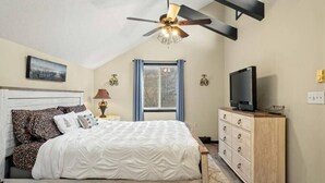 Une chambre à coucher avec un lit, une commode, un téléviseur et un ventilateur de plafond.