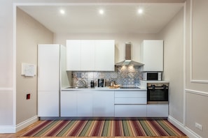 A compact kitchen with white cabinetry, a microwave, a stove, and a patterned backsplash. - Apartment 'Alberto' with Wi-Fi and Air Conditioning (Montecatini Terme)