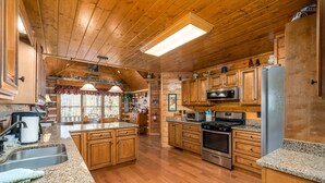 Une cuisine spacieuse dotée de meubles en bois, de plans de travail en granit, d’appareils électroménagers en acier inoxydable et d’un grand îlot central.