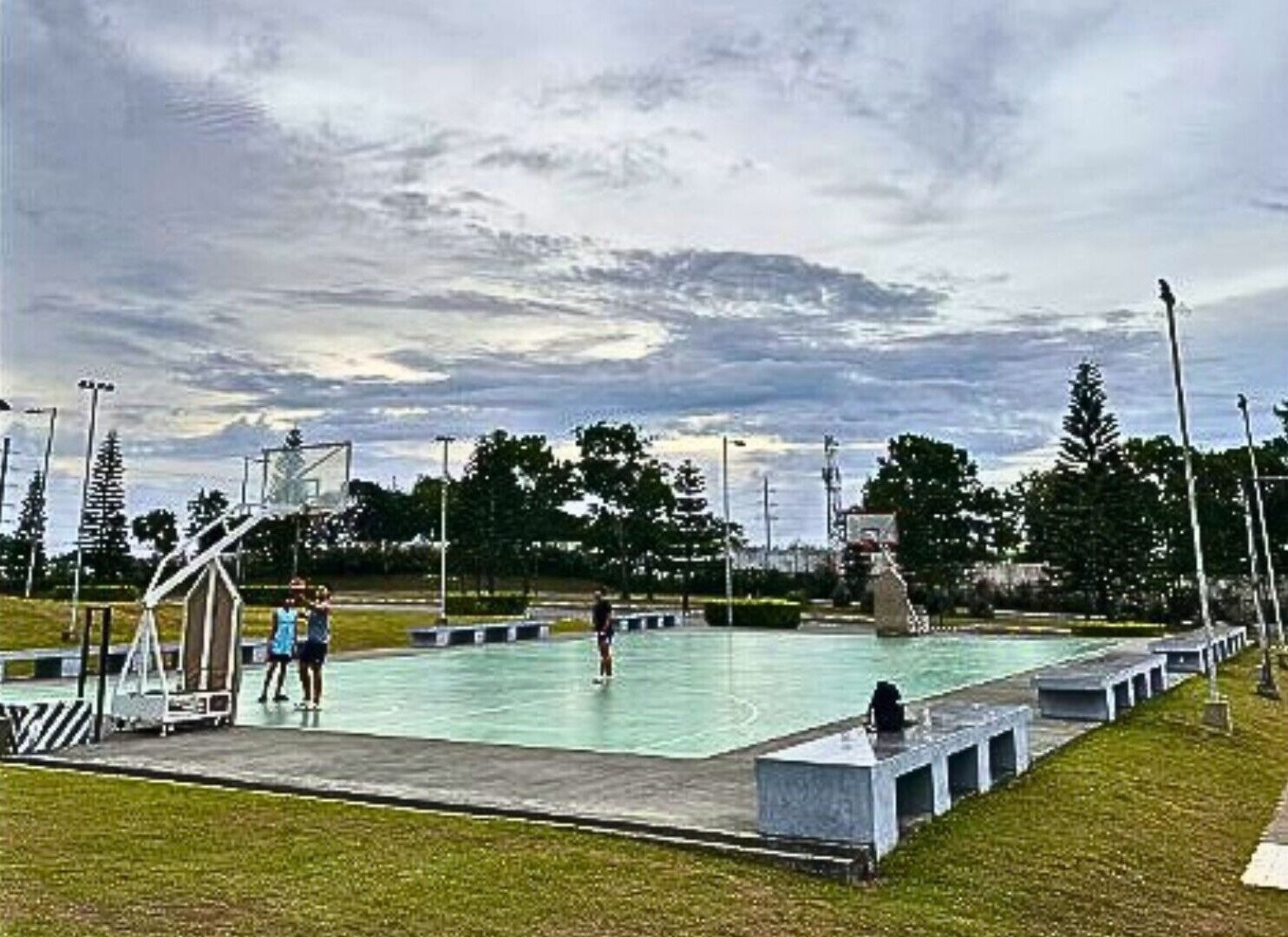 Une piscine avec un terrain de basket et un espace de jeux pour enfants.