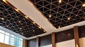 Eine großzügige Lobby mit hoher Decke, die ein geometrisches Muster aufweist, großen Fenstern und modernen Sitzbereichen.