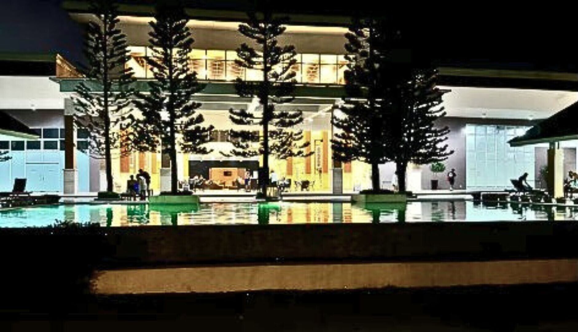 A hotel with a pool area, outdoor seating, and a well-lit entrance.