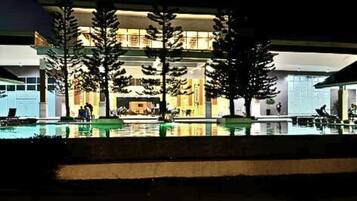 A hotel with a pool area, outdoor seating, and a well-lit entrance.
