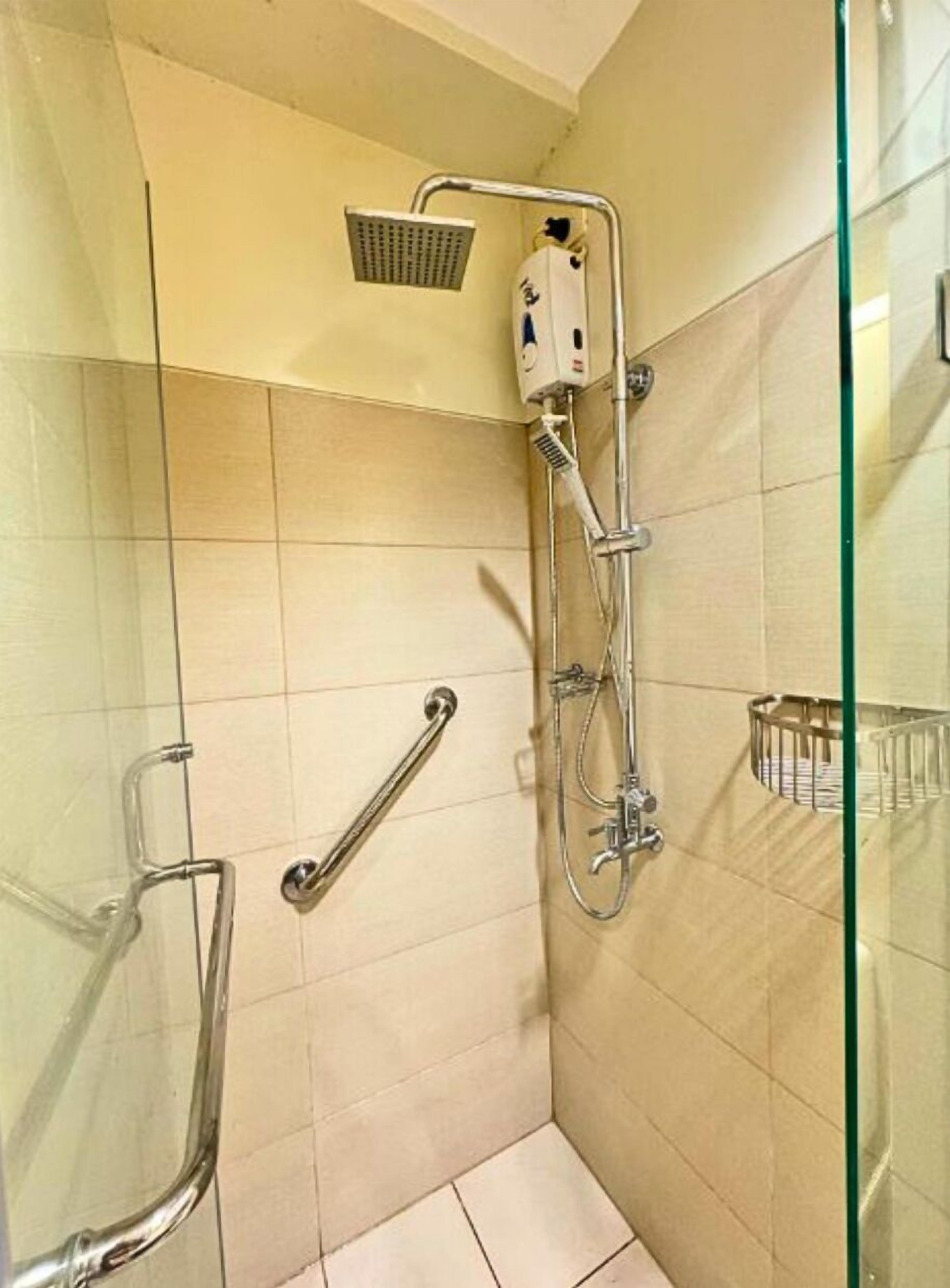 Ein kleiner, abgeschlossener Duschbereich mit Handbrause, Duscharmatur und Wasserhahn.