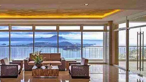 Ein großzügiger Wohnbereich mit einem großen Fenster und Blick auf das Meer und die Berge.
