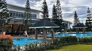 Ein Hotel mit Schwimmbad, Lounge-Bereich und einem großzügigen Gebäude mit Glasfassade.