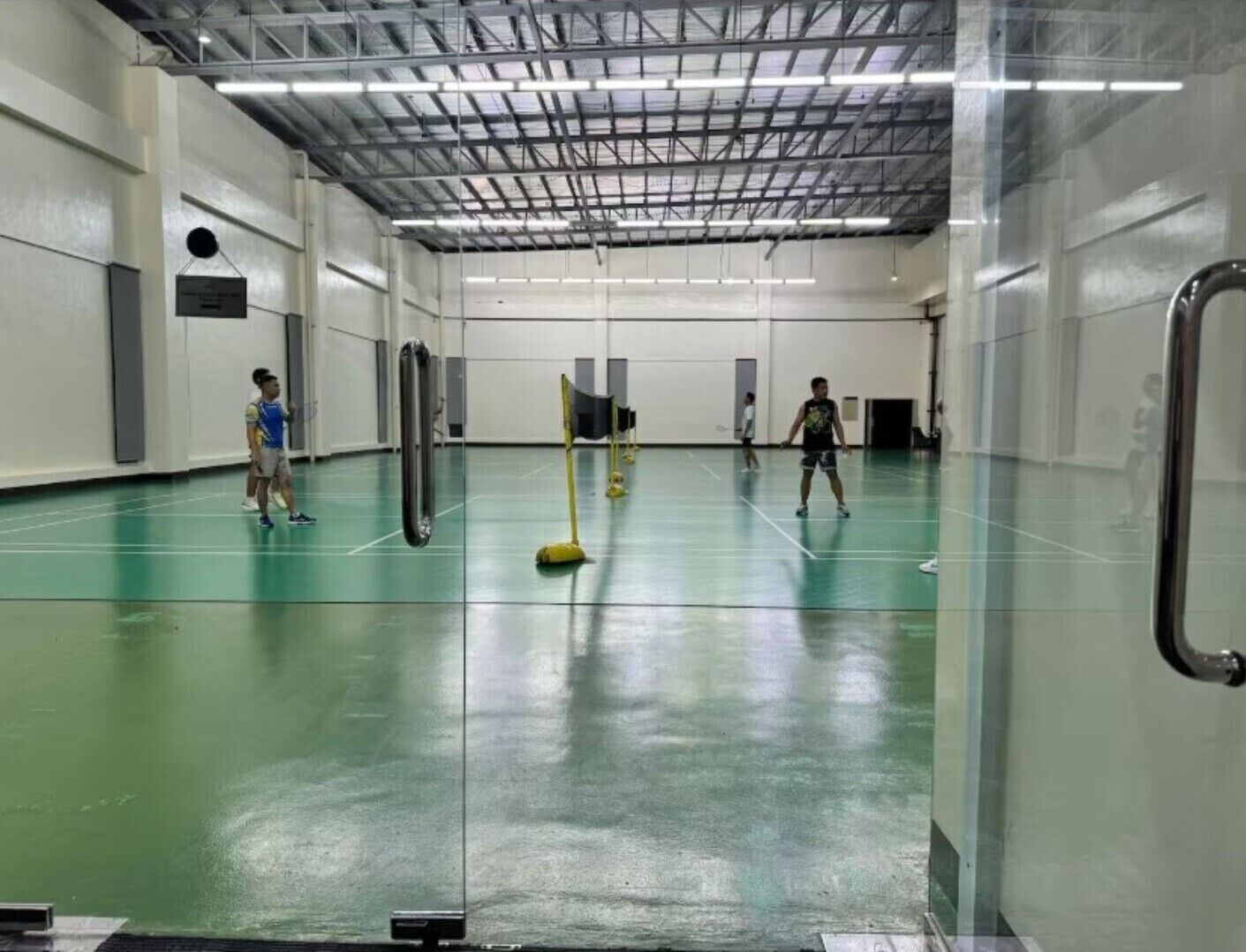 An indoor badminton court with a high ceiling and metal beams.