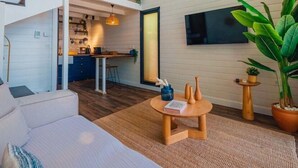 Un interior moderno con techo estilo loft, un comedor, una cocina y una sala de estar con una planta grande.