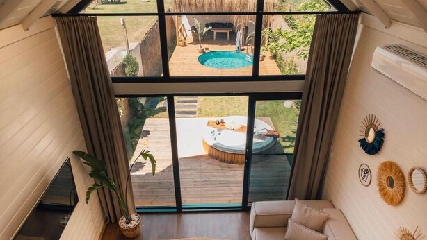Una habitación acogedora con un amplio ventanal, un sofá, una mesita de café y un televisor.