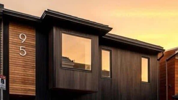 Une maison moderne à deux étages, dotée d’une façade noire et en bois, de grandes fenêtres et d’un numéro bien visible, le « 95 ».