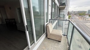 Un balcón con zona de estar acolchada, ventanas amplias y vista panorámica de la ciudad.