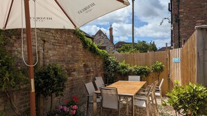 A wooden patio with a table and chairs, surrounded by a brick wall and a wooden fence. - The Bear Hotel (Wareham)