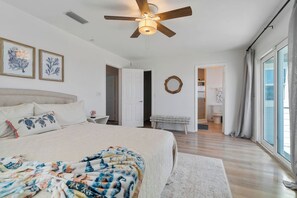 A bedroom with a large bed, a ceiling fan, and a view of the bathroom. - Renovated beachfront retreat within walking distance to three outstanding restaurants! Fall asleep to the sounds of crashing waves on the beautiful Northeast Coast of Florida, just 5 miles from America’s oldest city, St. Augustine! (St. Augustine)