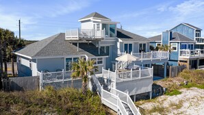 A coastal house with multiple levels, a balcony, and a pool.
