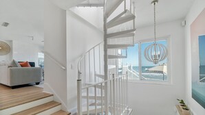 A staircase with white railings leading to a balcony with a view of the ocean.
