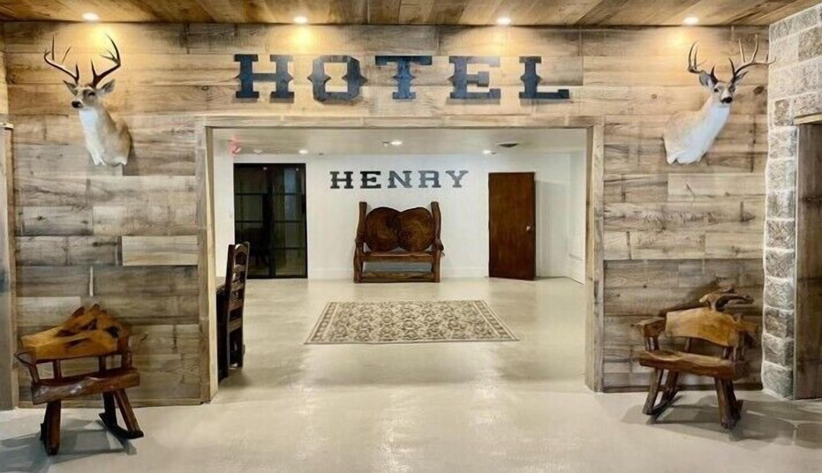 A hotel entrance with a wooden facade, a sign reading "HOTEL HENRY", and antler decorations on the walls.