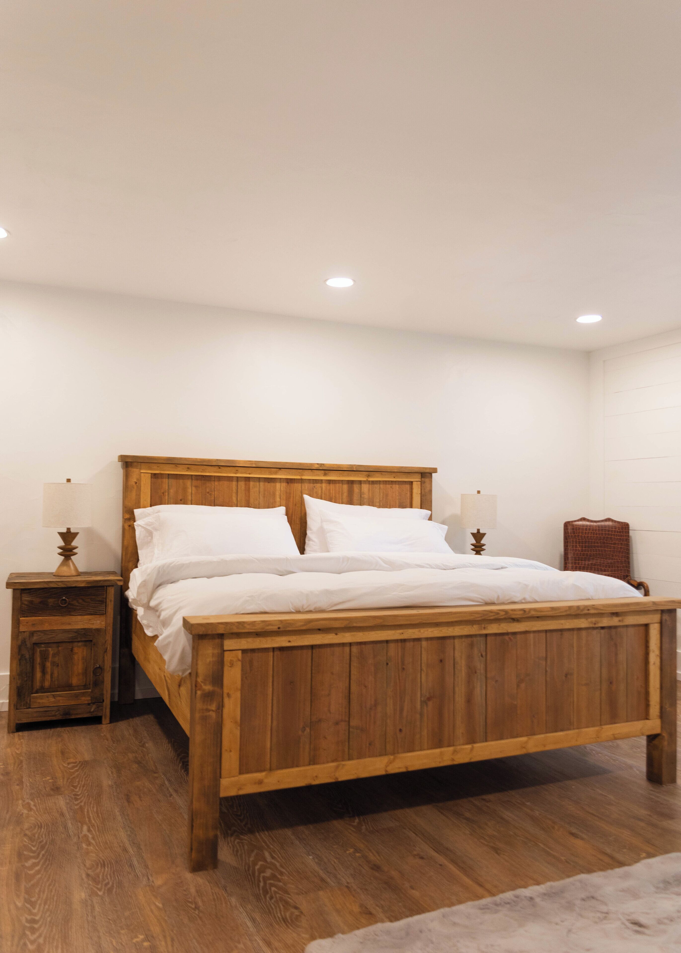 A wooden bed in a room with white walls and a wooden floor.