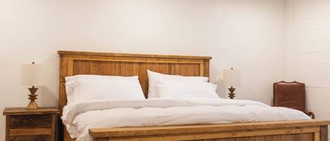 A wooden bed in a room with white walls and a wooden floor.