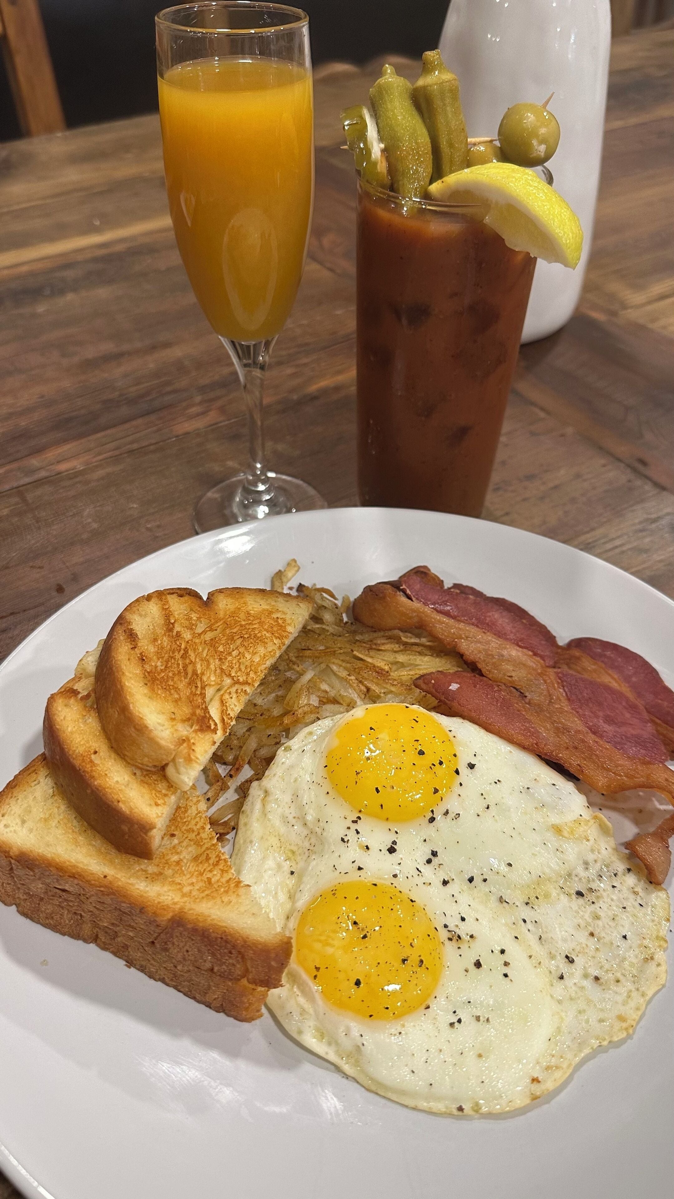 Ein Teller mit Toast, Eiern, Speck und einem Glas Orangensaft.