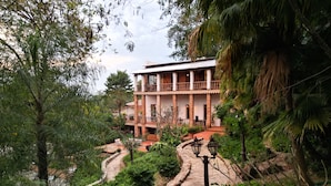 Un edificio con un viale curvo in pietra che conduce a un balcone con ringhiera.