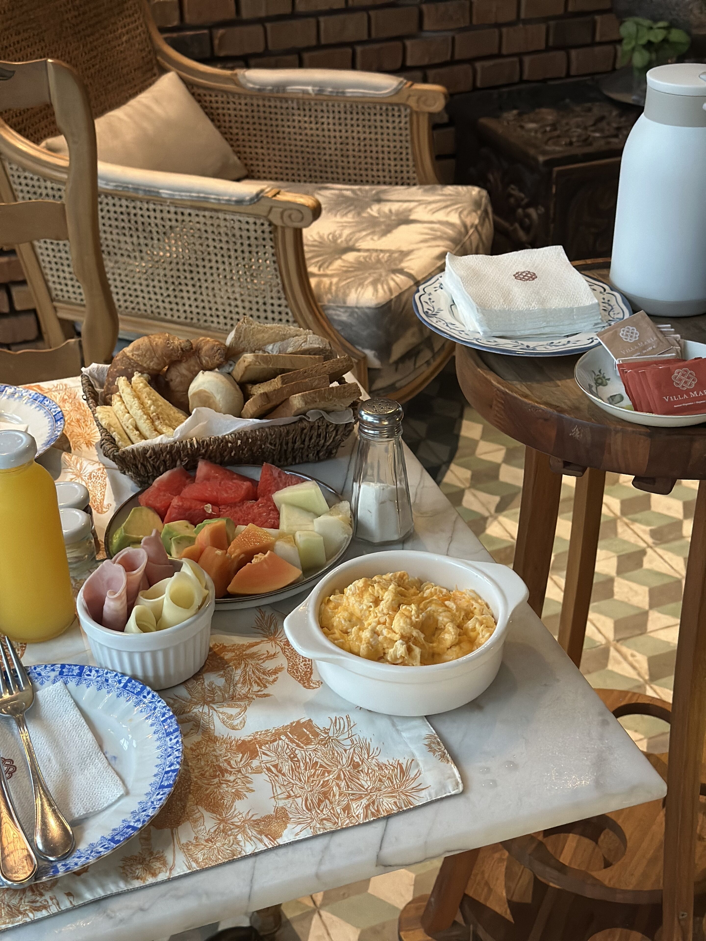 Mesa de pequeno-almoço com vários alimentos, incluindo pão, fruta e ovos.