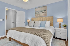A bedroom with a bed, bedside lamps, a door, and a painting on the wall.