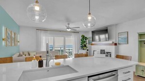 A modern kitchen with a central island, white cabinetry, and pendant lighting. - Oceanfront 2BR Suite | Boardwalk-Parking-Sleeps 5 (Carolina Beach)
