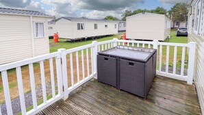 A mobile home with a fenced deck and a small outdoor seating area. - Beachcombers Barmouth Bay Holiday Park (Talybont)