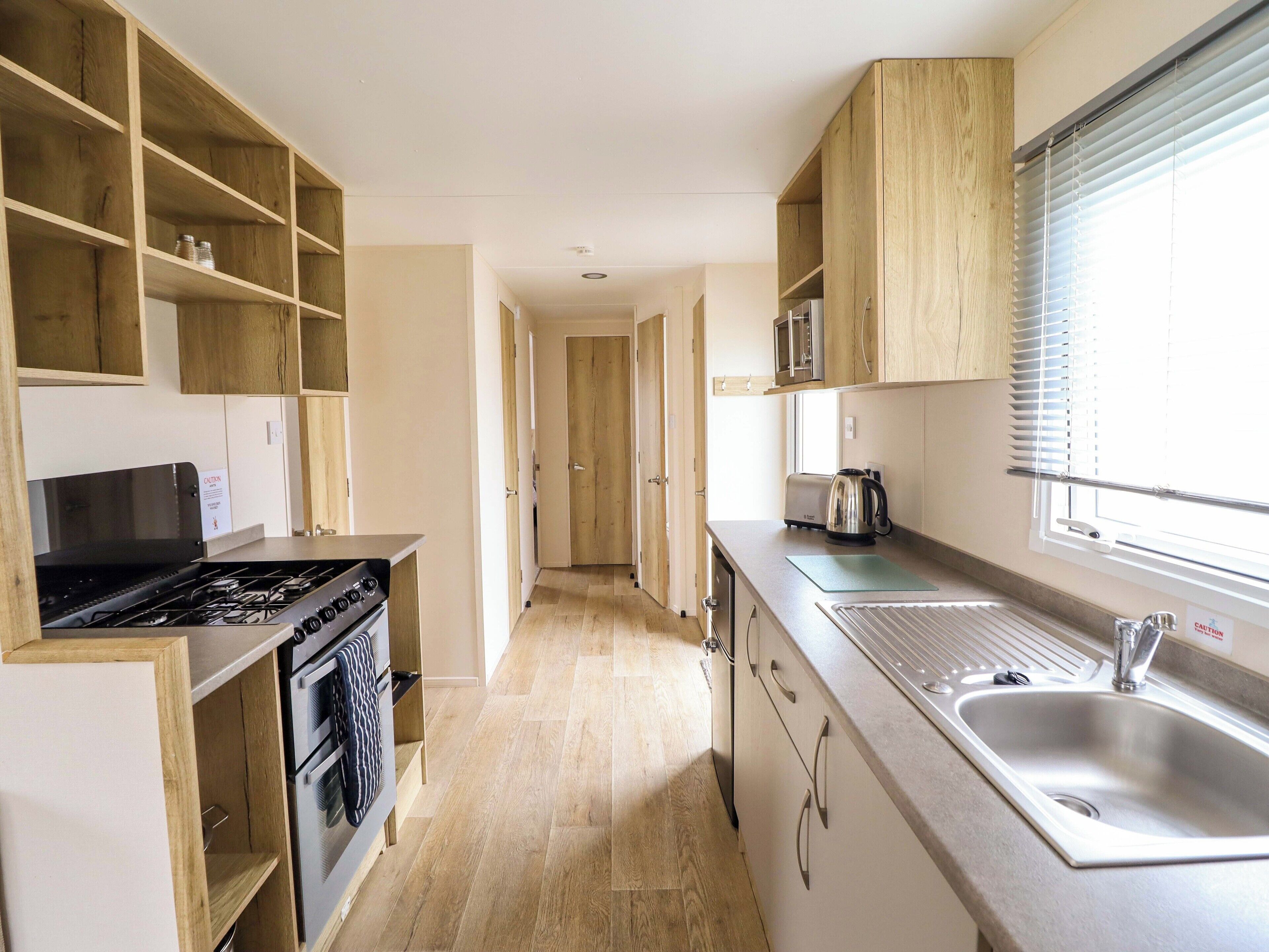 Cocina pequeña con armarios de madera, una hornalla y un lavamanos.