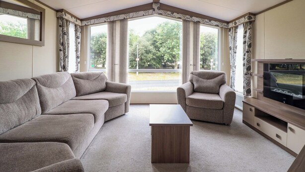 A living room with a sofa, armchair, coffee table, and TV.