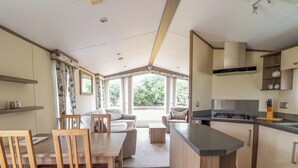 A modern kitchen with a dining area, wooden furniture, and a view of the outdoors.
