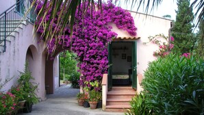 Un sendero estrecho que conduce a un edificio, con una cama visible a través de una puerta abierta.